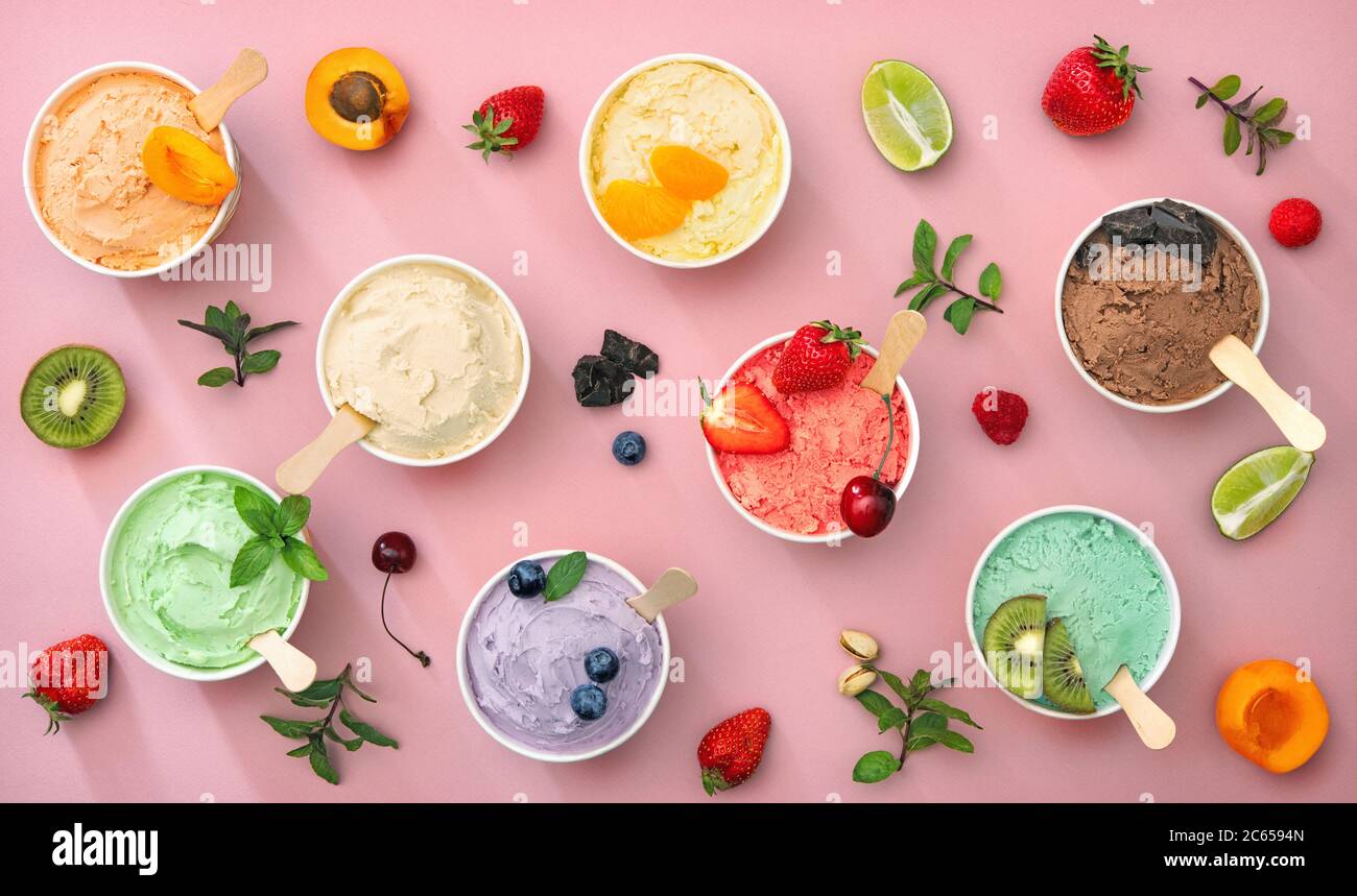 Various colorful ice cream sorts with fruits in paper cups on pink