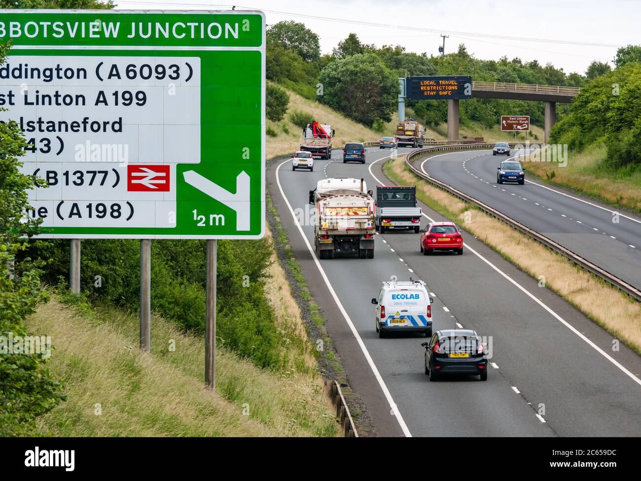 East Lothian, Scotland, United Kingdom, 7th July 2020. Covid-19 new message on A1 gantry: the third version of the pandemic message appears on overhead gantry near Haddington which reads 'Local Travel Restrictions Stay Safe' as Scotland eases into Phase 3 expected next week. The traffic on the dual carriageway is much heavier than has been apparent in recent months Stock Photo