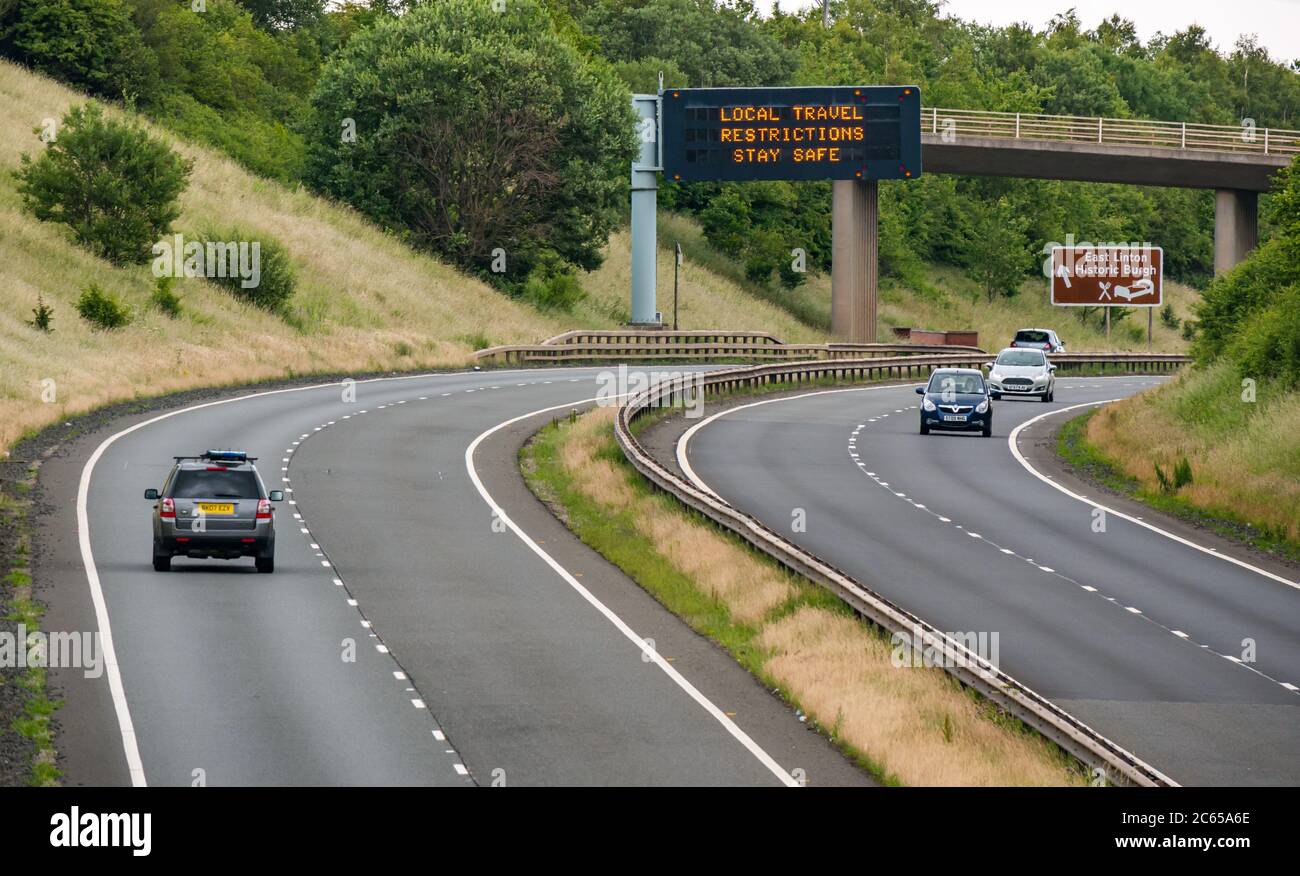 East Lothian, Scotland, United Kingdom, 7th July 2020. Covid-19 new message on A1 gantry: the third version of the pandemic message appears on overhead gantry near Haddington which reads 'Local Travel Restrictions Stay Safe' as Scotland eases into Phase 3 expected next week. The traffic on the dual carriageway is much heavier than has been apparent in recent months Stock Photo