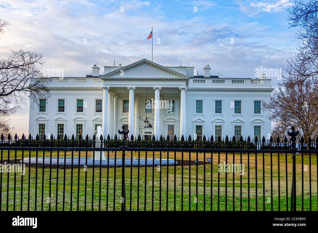Early morning sunlight case on the front entrance of the White House, Presidential residence with fountain and iron fence on the grounds in foreground Stock Photo