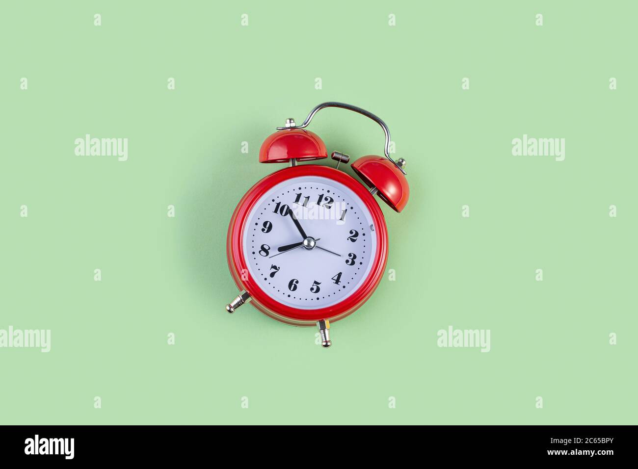 Red vintage alarm clock on light green color background. Alarm clock with place for text. Time management concept, business planning Stock Photo
