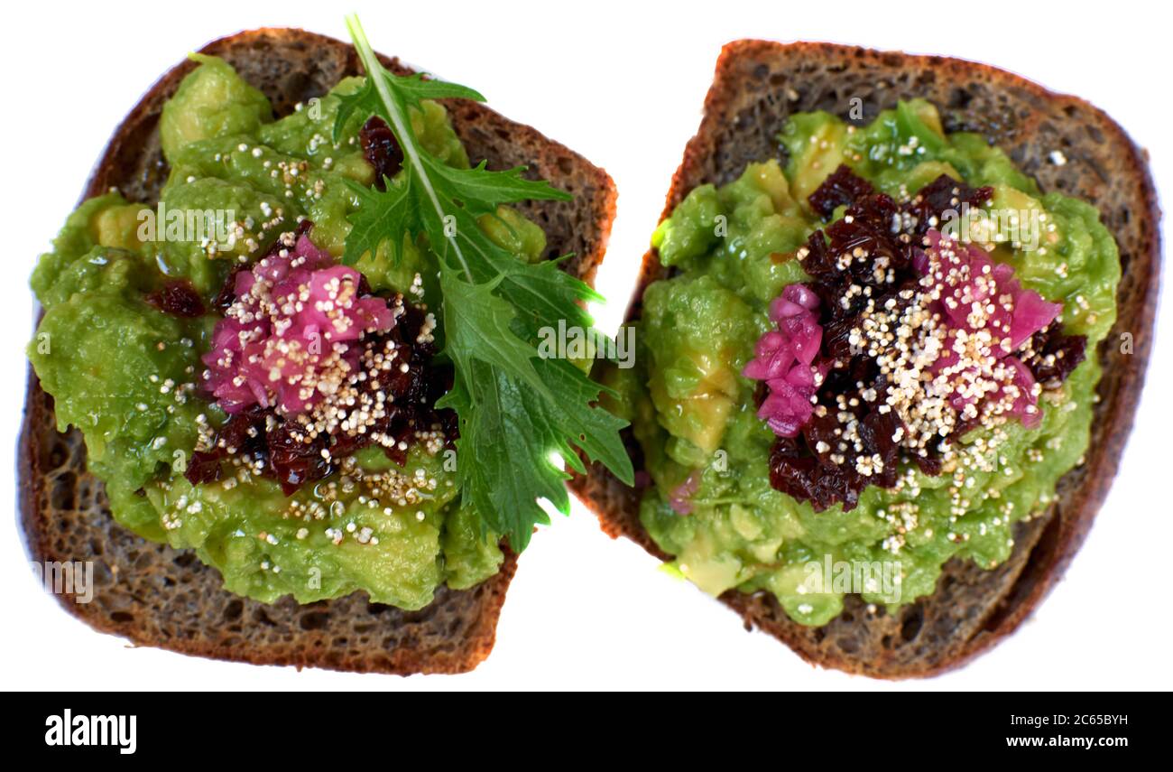 Healthy mashed avocado toasts for breakfast or lunch with rye whole grain bread, sliced avocado and sesame seeds, salt and pepper. Vegetarian. Plant Stock Photo