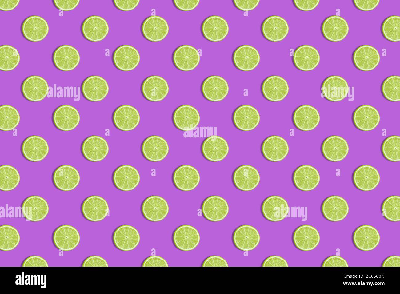 Colorful fruit seamless pattern of fresh lime slices on a purple background. Trendy sunlight Summer pattern. Minimal summer concept. flat lay food tex Stock Photo