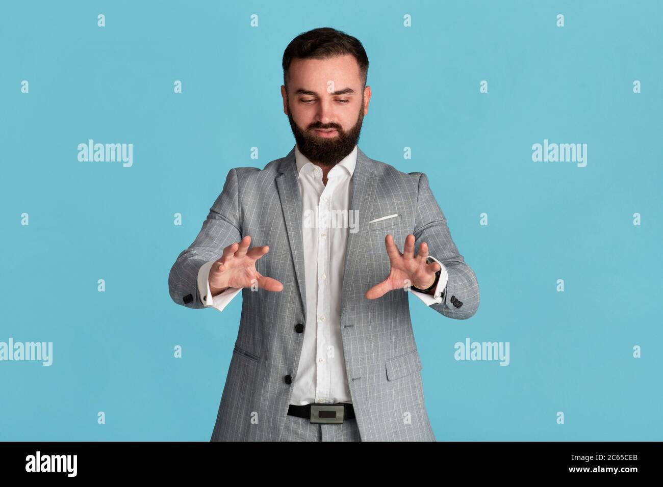 Serious young entrepreneur touching interactive virtual screen on blue background, space for design Stock Photo