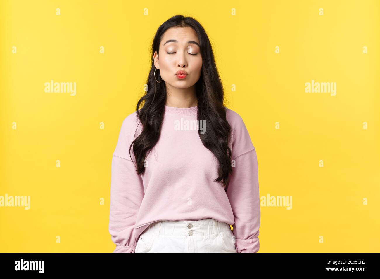 Lifestyle, emotions and advertisement concept. Dreamy pretty korean girl waiting for kiss, close eyes and folding lips, have romantic moment on date Stock Photo