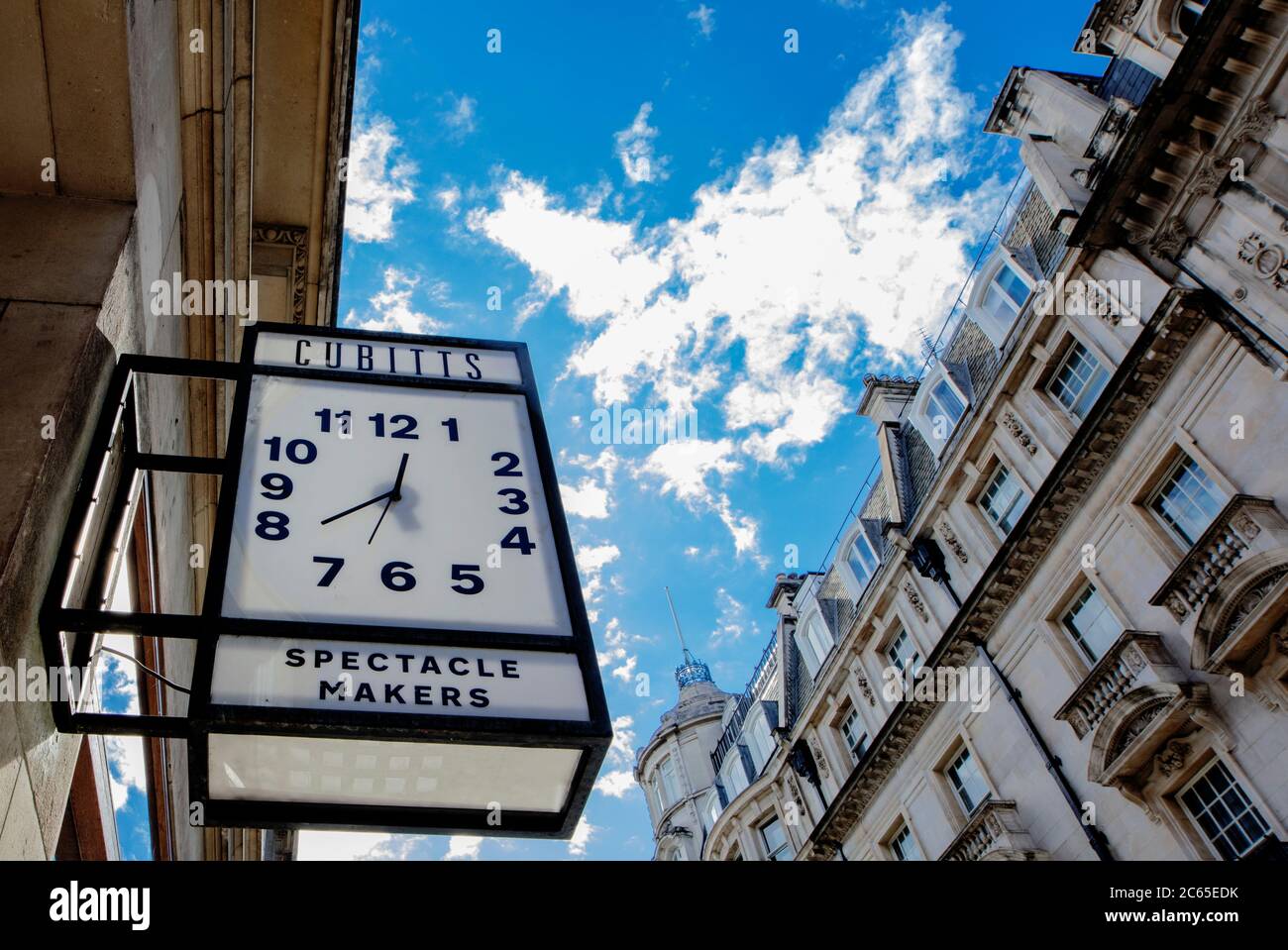 Dramatic cloudscape behind clock sign advertising Cubitt's spectacle makers in Jermyn St, London Stock Photo