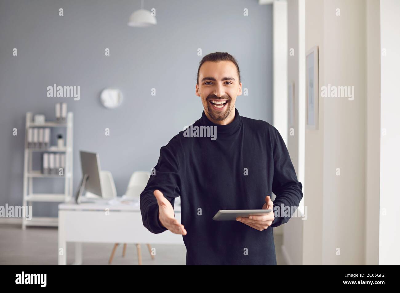 Handshake offering. A businessman offers a handshake while standing in an office. Stock Photo