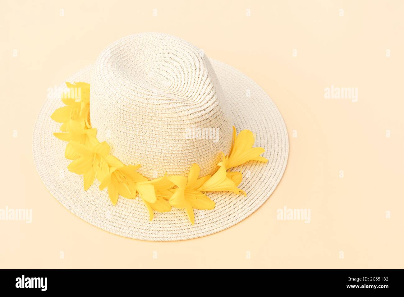 Straw hat with with yellow lily flowers on pastel background. Stylish retro design template. Yellow background. Summer fashion concept. Copy space. Stock Photo