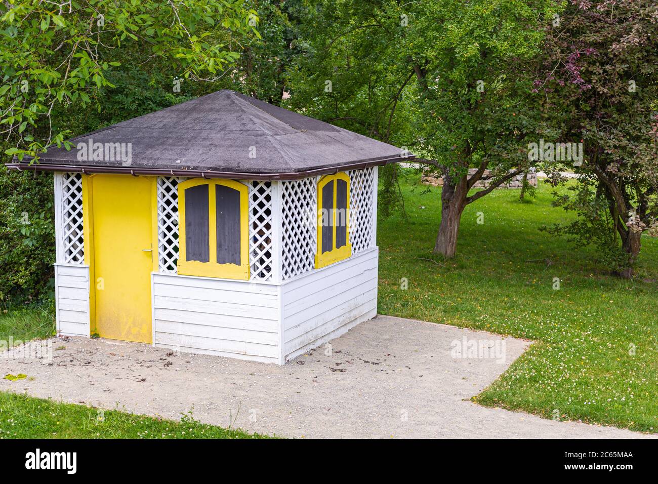Wooden gazebo in the city park. A small, white house. An ideal place to rest. Stock Photo
