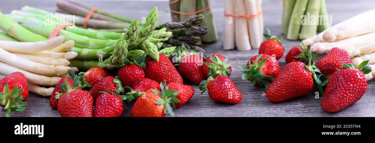 Grüne Spargel, weiße Spargel und frische Erdbeeren dekoriert auf einem rustikalen Holztisch Stock Photo