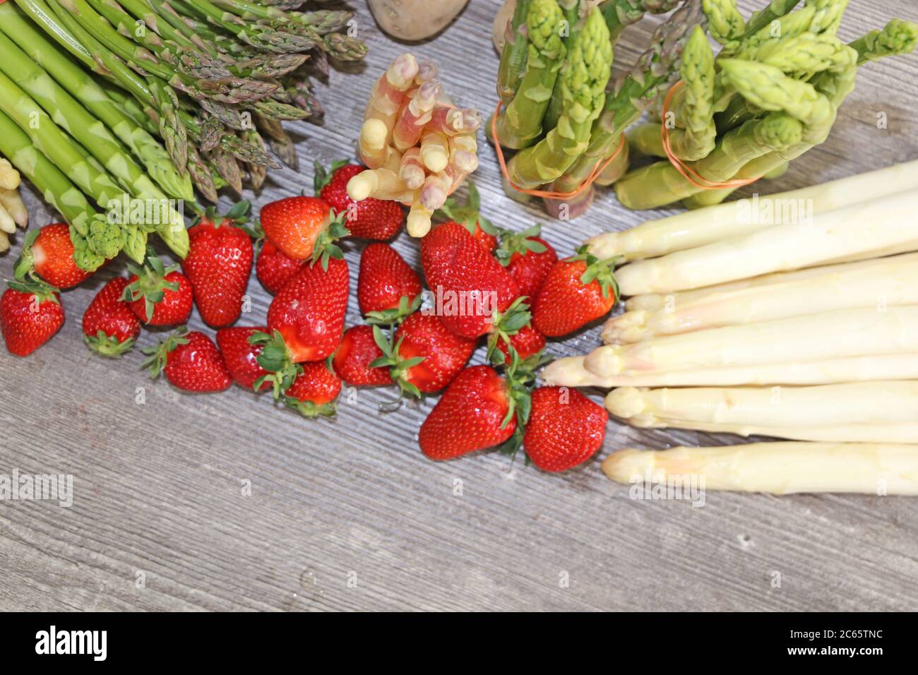 Grüne Spargel, weiße Spargel und frische Erdbeeren dekoriert auf einem rustikalen Holztisch Stock Photo