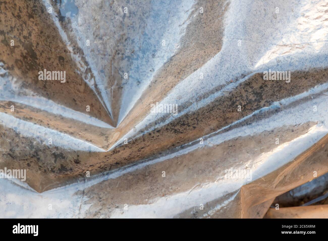 Misted polyethylene film lies on dirty ground, the greenhouse effect illustration Stock Photo