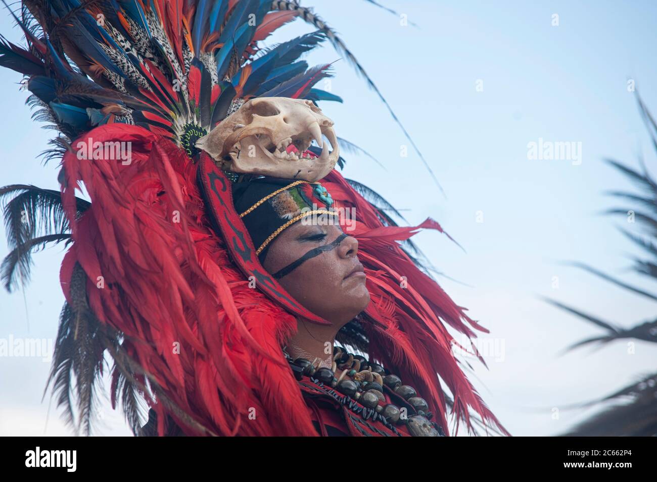 Close up unknown Mayan woman with traditional costume with feather headdress and a skull on her forehead - she dances in a tribal dance. Stock Photo