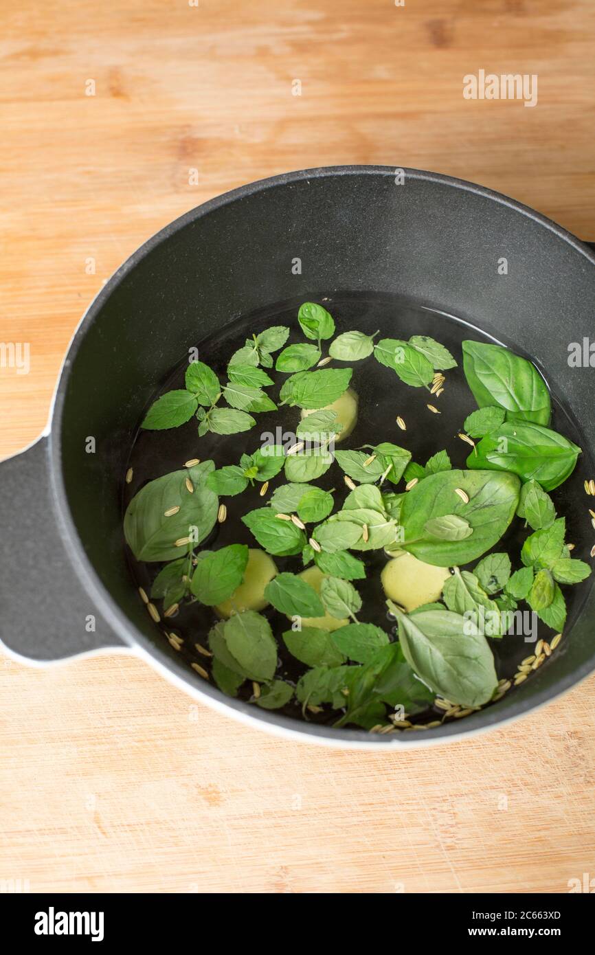 Make your own Ayurveda drink: Add the ingredients to the water that is no longer boiling and put the lid on the pot. Stock Photo