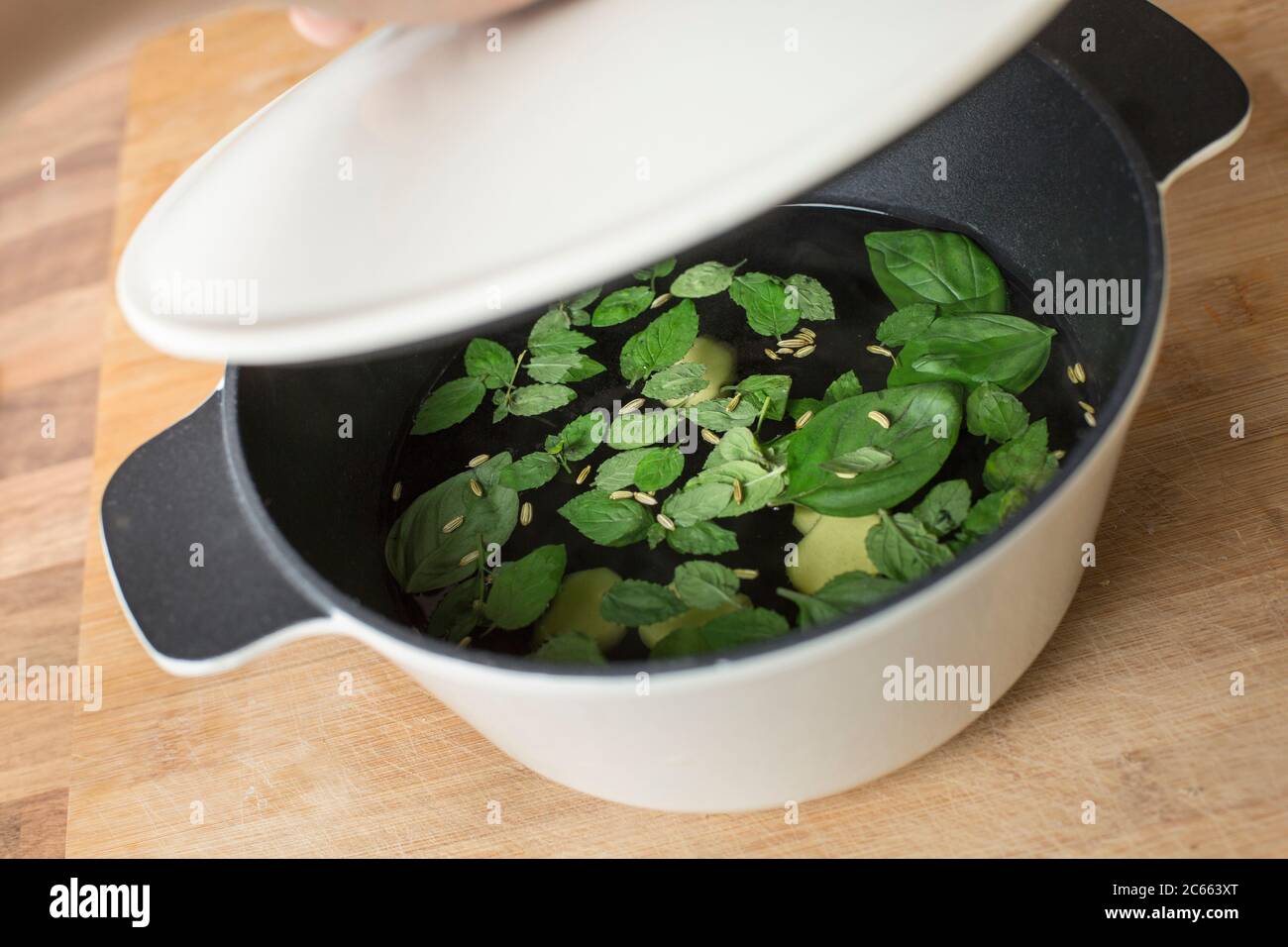 Make your own Ayurveda drink: Add the ingredients to the water that is no longer boiling and put the lid on the pot. Stock Photo