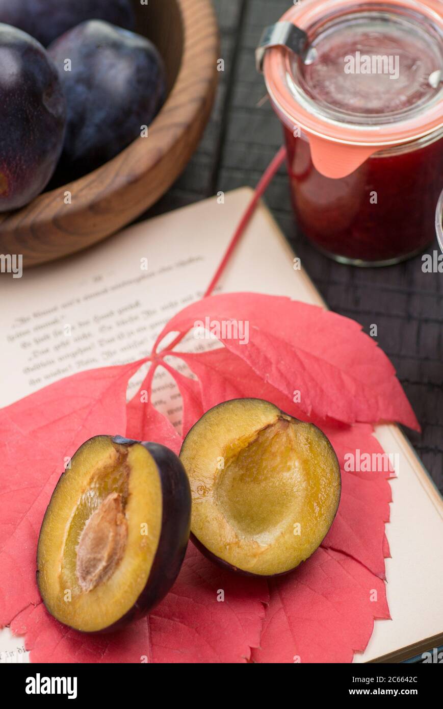 opened book, autumn leaf, plums and stewed plums Stock Photo
