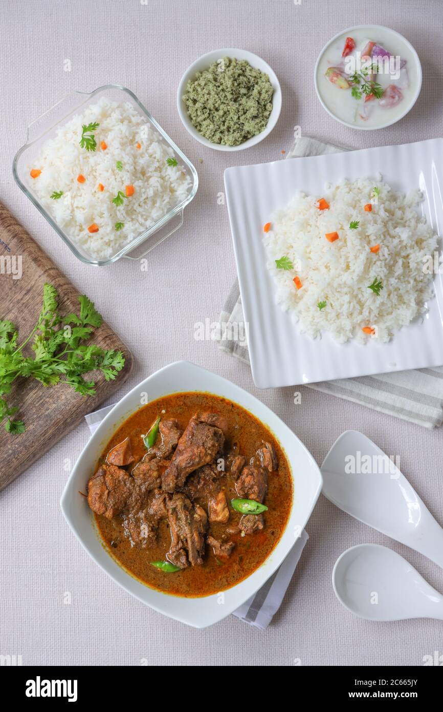 Chicken masala or curry with ghee rice or biriyani,biryani rice placed in a square tablewares white in colour with green coconut mint chutne and veg s Stock Photo