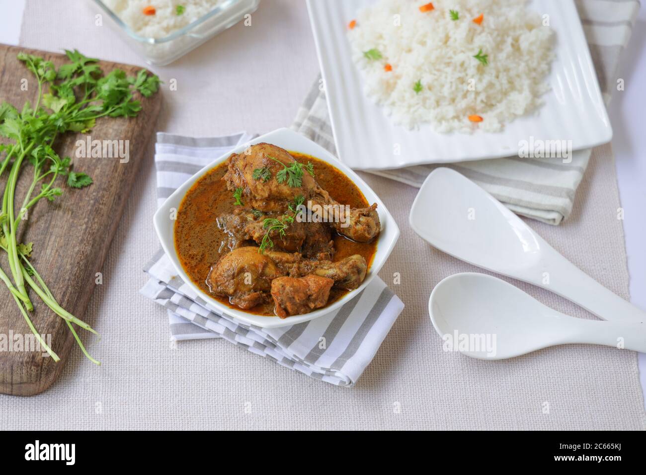 Chicken masala curry with ghee rice or biryani rice, placed in a square tablewares white in colour with green coconut mint chutne and raita Stock Photo