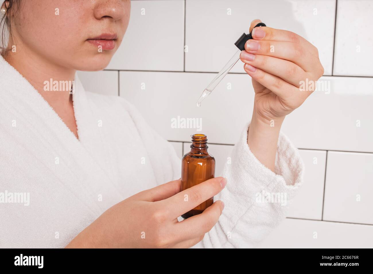 Hands of young woman after shower going to apply beauty serum Stock