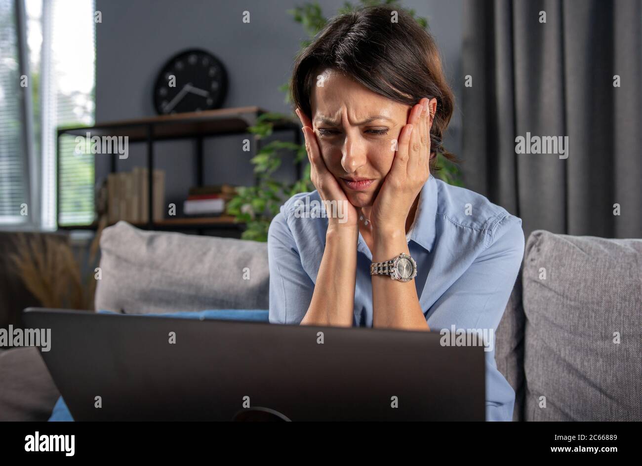 Mature woman feeling sad while looking at computer screen Stock Photo