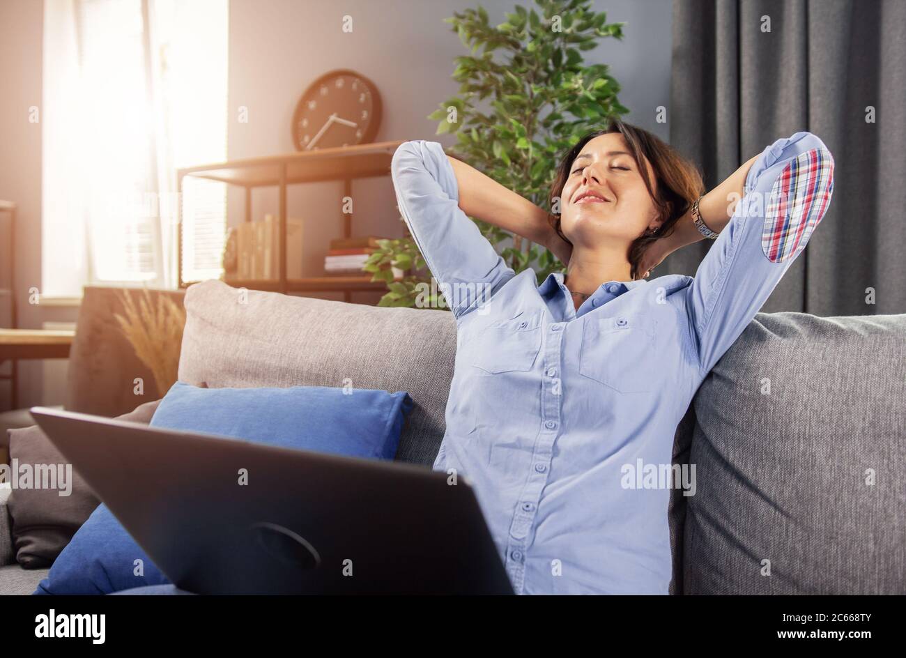 Charming lady relaxing on couch during remote work on laptop Stock Photo