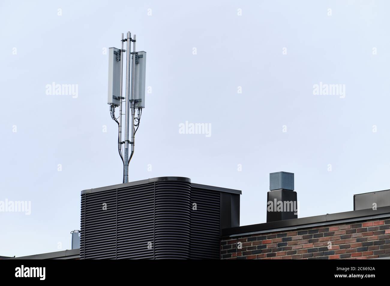 Cellular phone network telecommunication tower on the building roof. Stock Photo