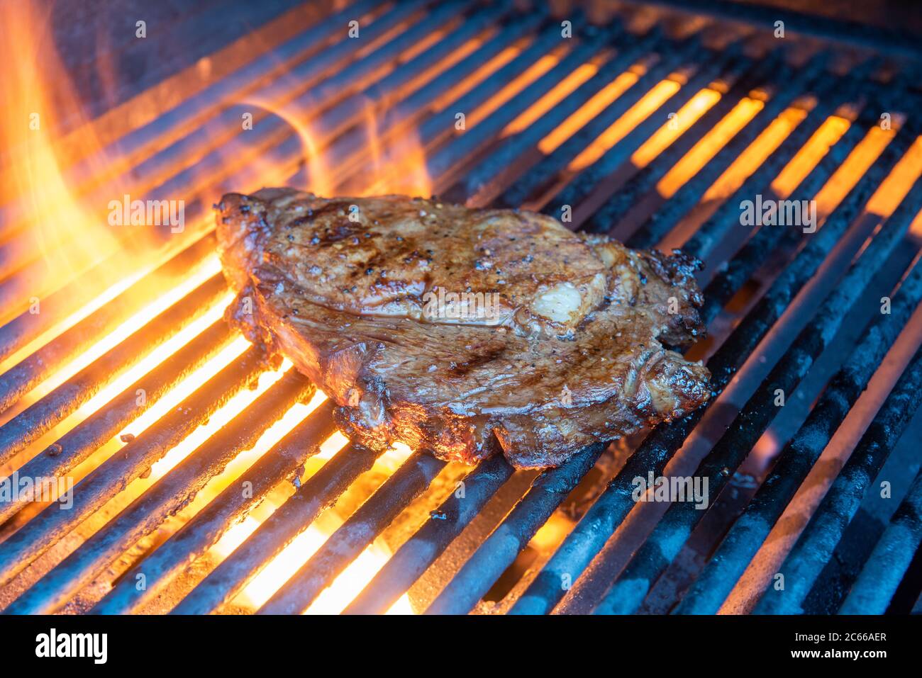 Ribeye steak being cooked on a grill with flame and smoke Stock Photo ...