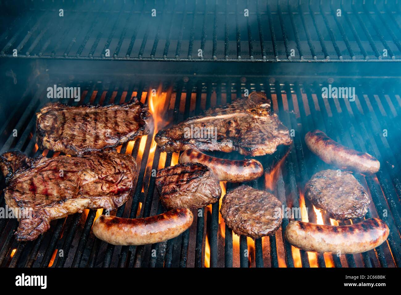 A grill full of different steaks including ribeye, Tbone, porterhouse