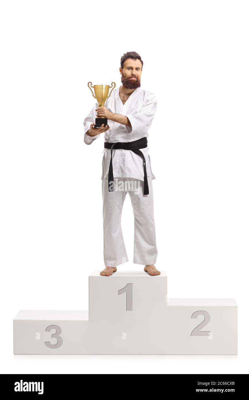 Full length portrait of a karate champion in kimono with a trophy cup on a  winners podium isolated on white background Stock Photo - Alamy