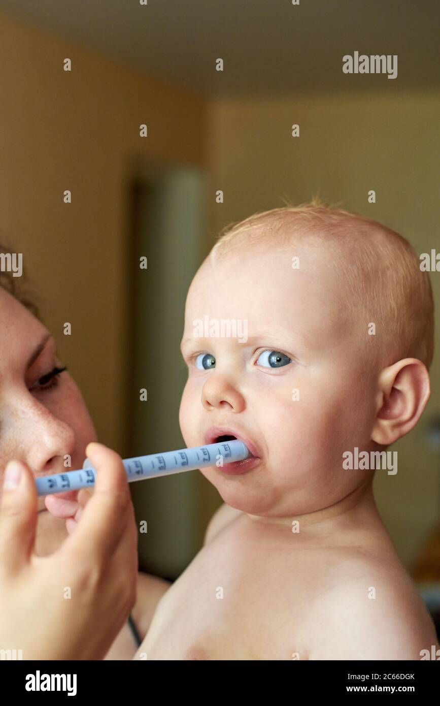 Mom gives her little child medicine through a syringe Stock Photo Alamy
