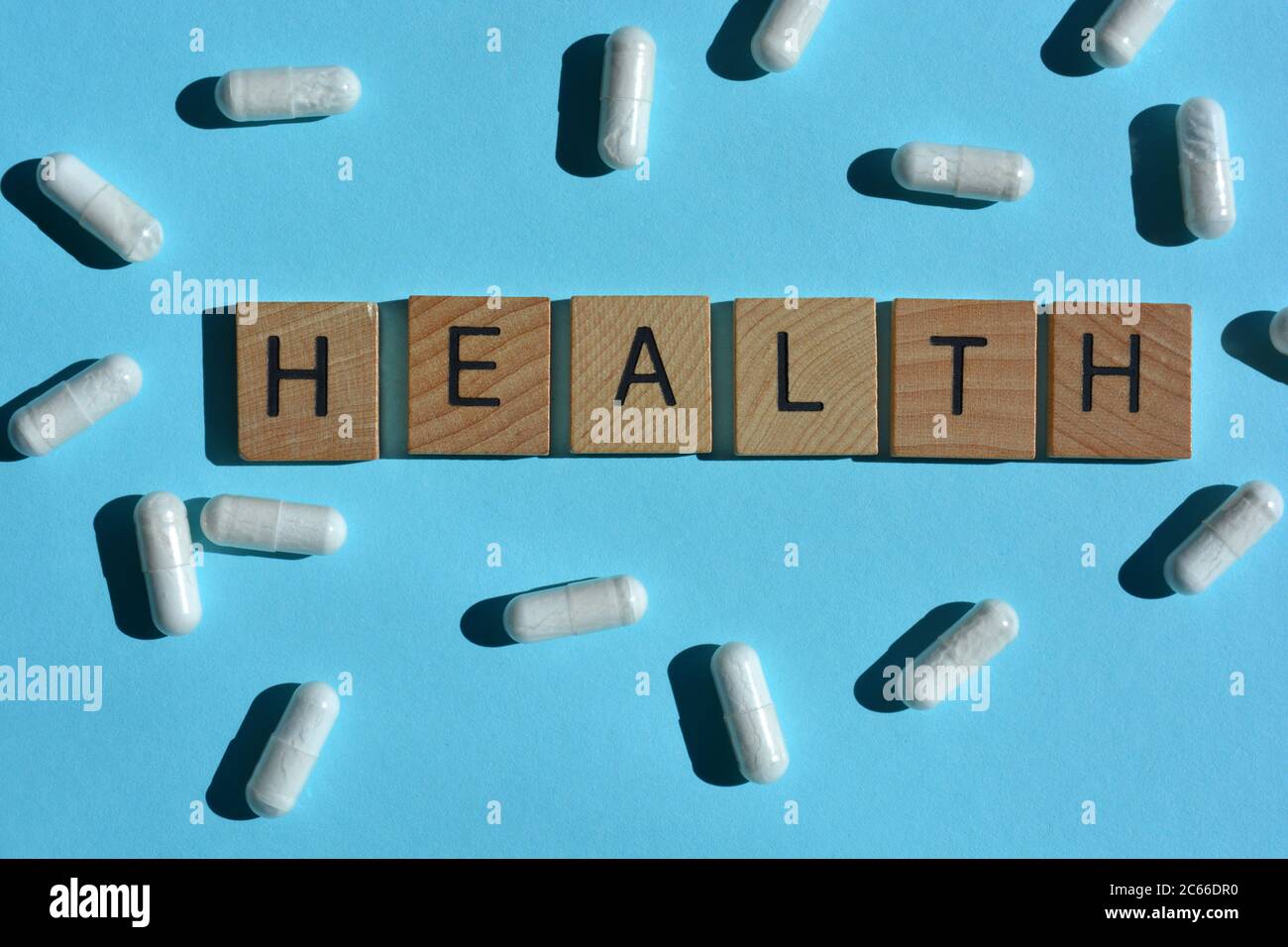 health-word-in-wood-alphabet-letters-and-white-capsules-on-blue-background-stock-photo-alamy