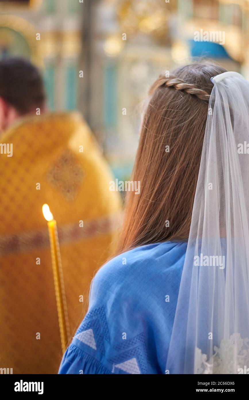 Bride with a candle in the church, the wedding ceremony in the Christian church. Rear view. Stock Photo