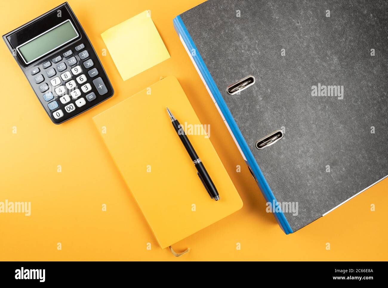 office work concept, above view of ring binder, note pad and calculator on orange background Stock Photo