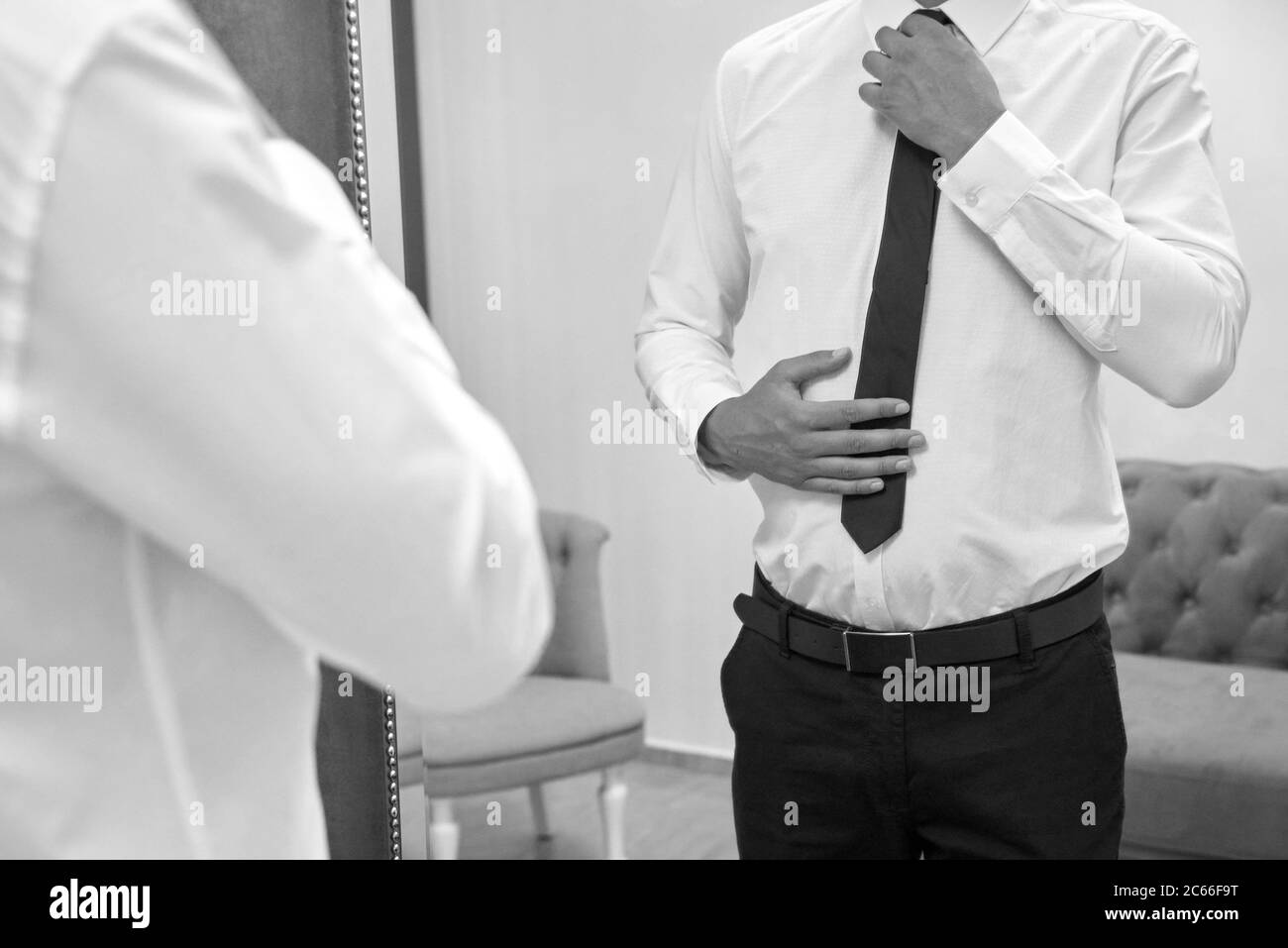 The groom straightens his tie before the wedding ceremony on his