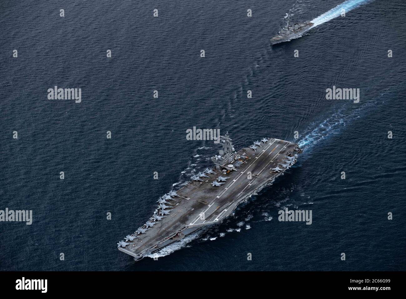 The U.S. Navy Nimitz-class aircraft carrier USS Ronald Reagan and Arleigh Burke-class guided missile destroyer USS Mustin steam in formation during dual-carrier operations July 6, 2020 in the South China Sea. Stock Photo