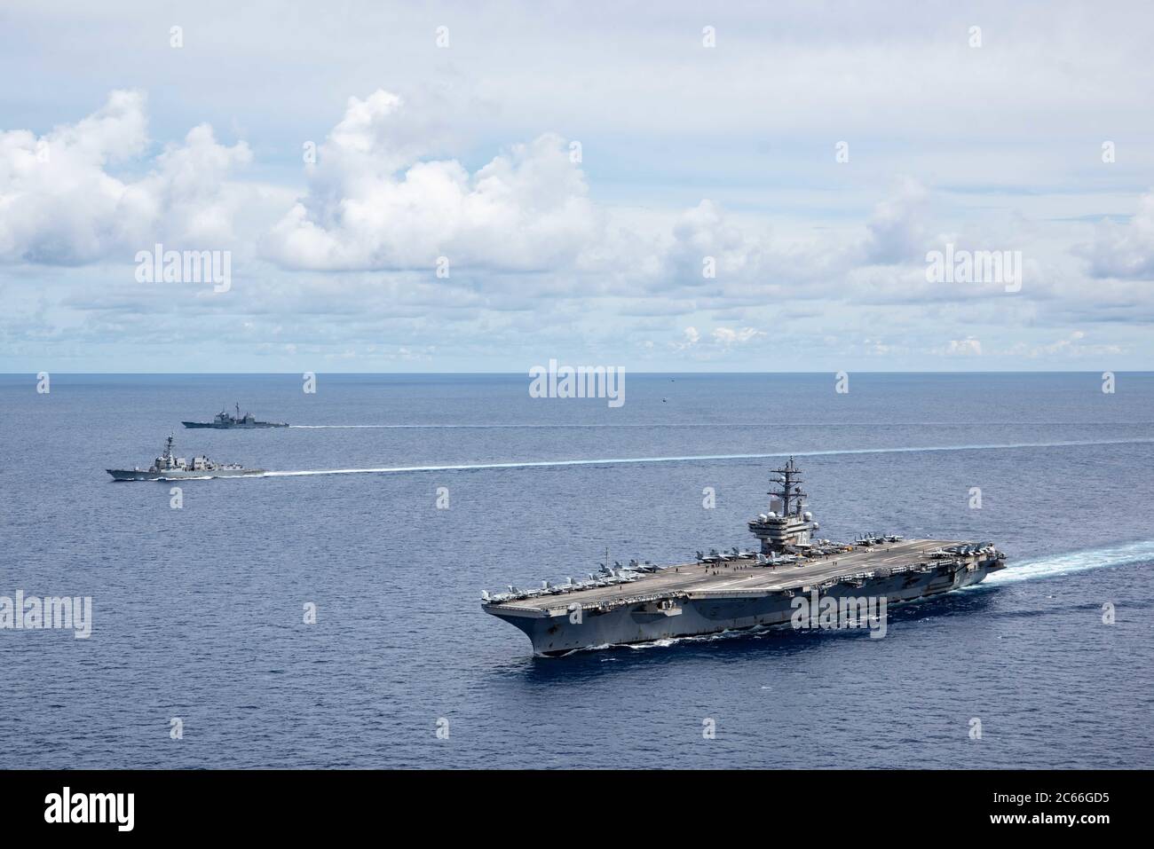 The U.S. Navy Nimitz-class aircraft carrier USS Ronald Reagan sails alongside the Arleigh Burke-class guided missile destroyer USS Mustin and the Ticonderoga-class guided missile cruiser USS Antietam during dual-carrier operations July 6, 2020 in the South China Sea. Stock Photo