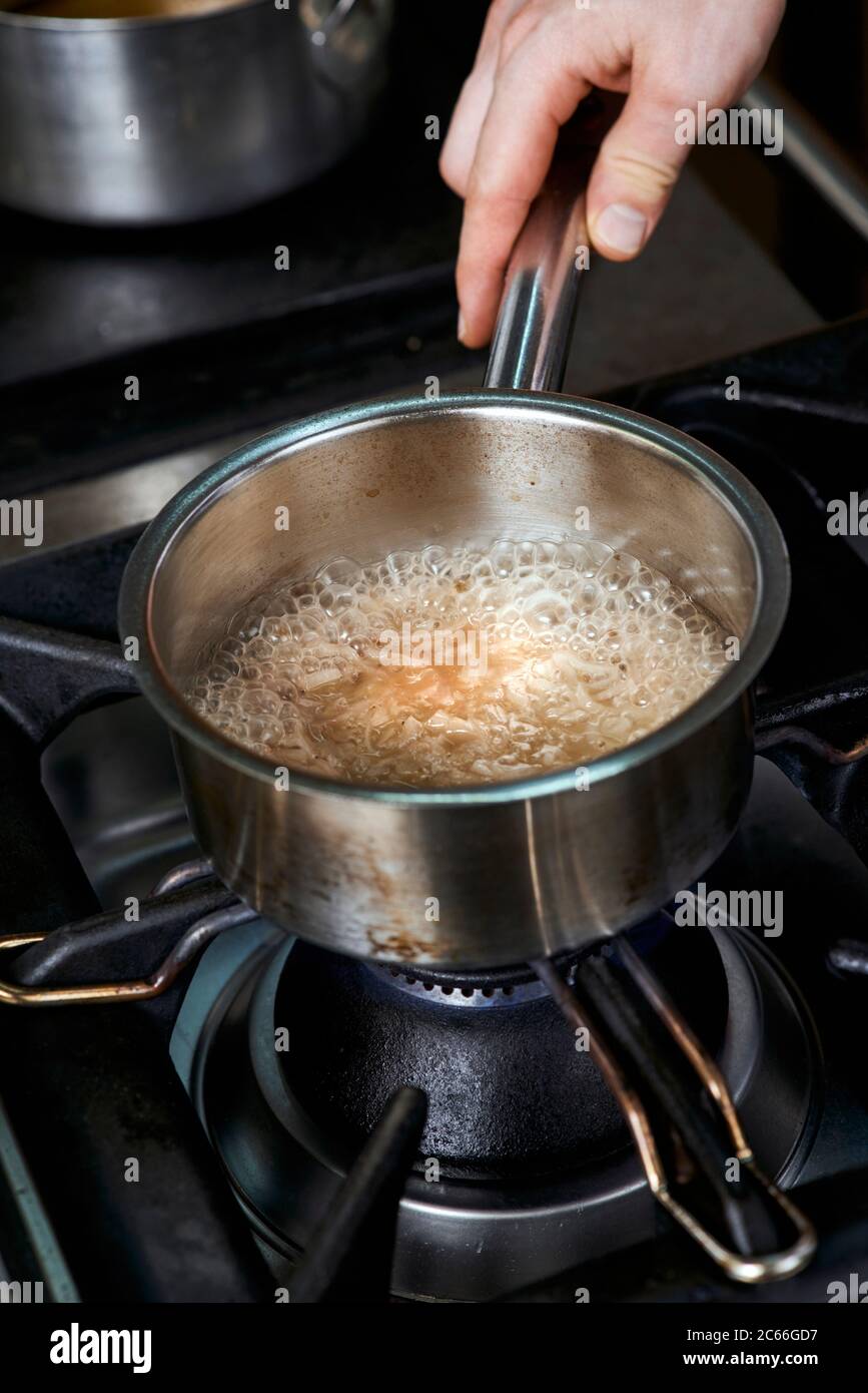 Preparation of Béarnaise Sauce step by step, wine and vinegar plus chopped shallots and herbs being boiled Stock Photo