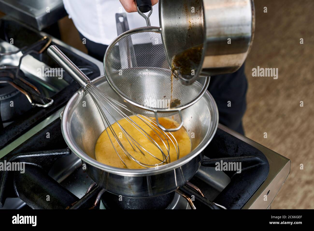 Preparation of Béarnaise Sauce step by step, reduction being strained through a sieve Stock Photo
