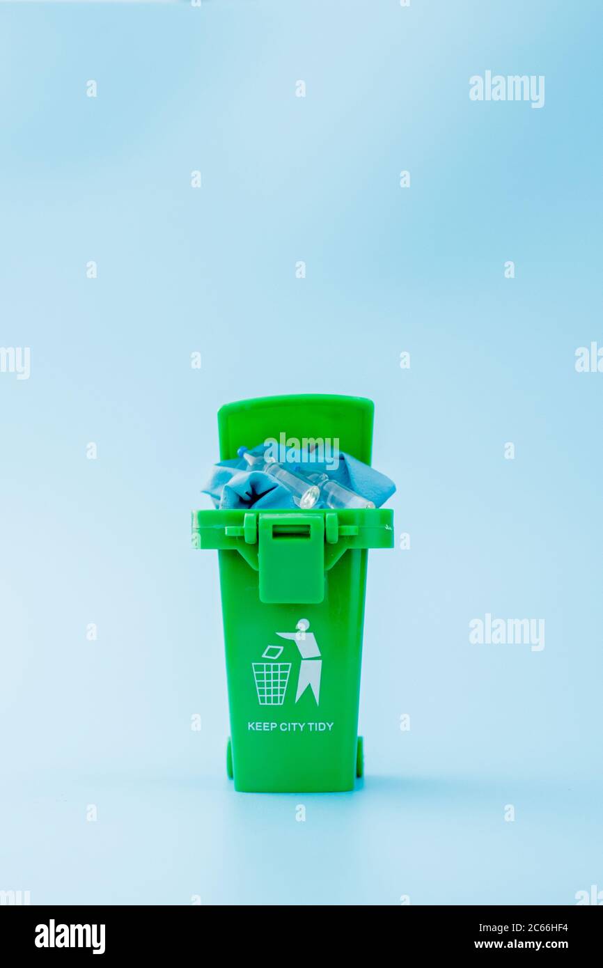 Green garbage, trash bin on blue background Stock Photo - Alamy