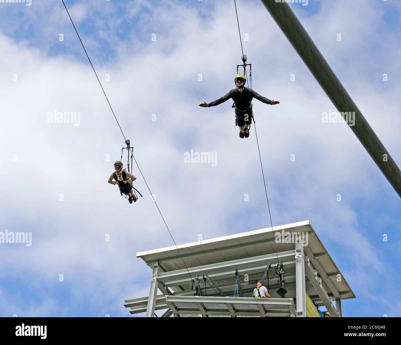 Two courageous tourists on a 1000 m-long slide down to the valley, at a height of 120 m above Rappbode Dam, on the longest zip-line in Europe Stock Photo