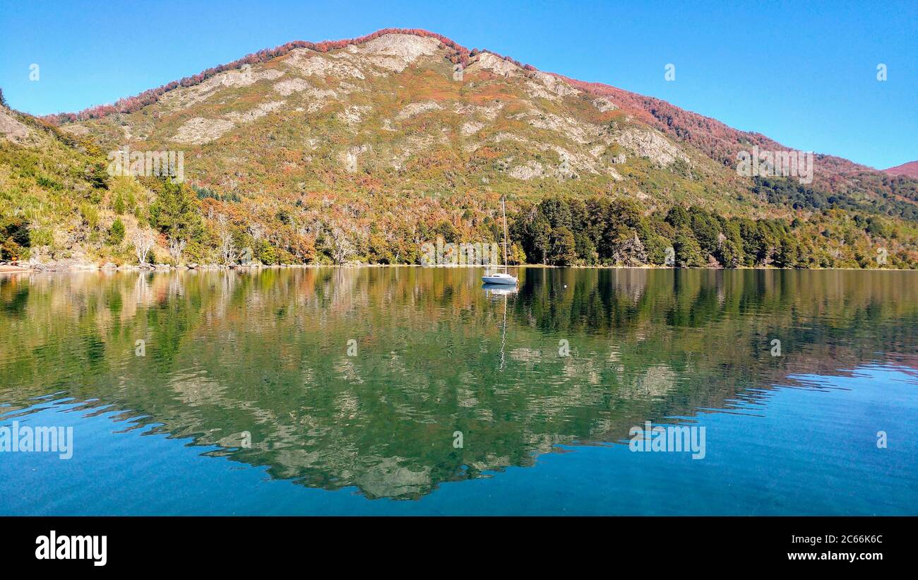 Mountain with red trees on the top reflected in the water, Lago Hermoso, Argentina Stock Photo