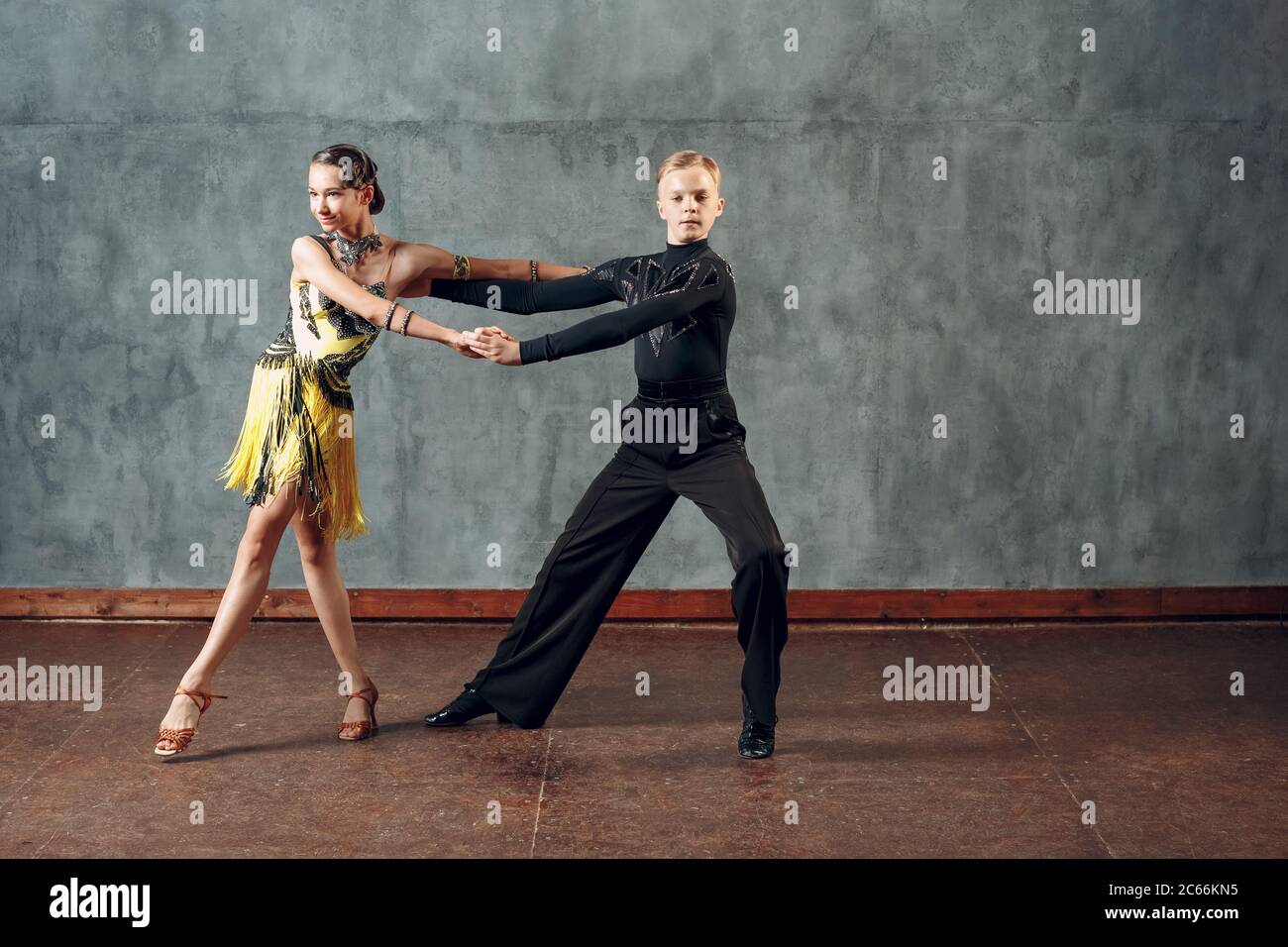 Young couple sport dancers dancing in ballroom dance cha cha cha