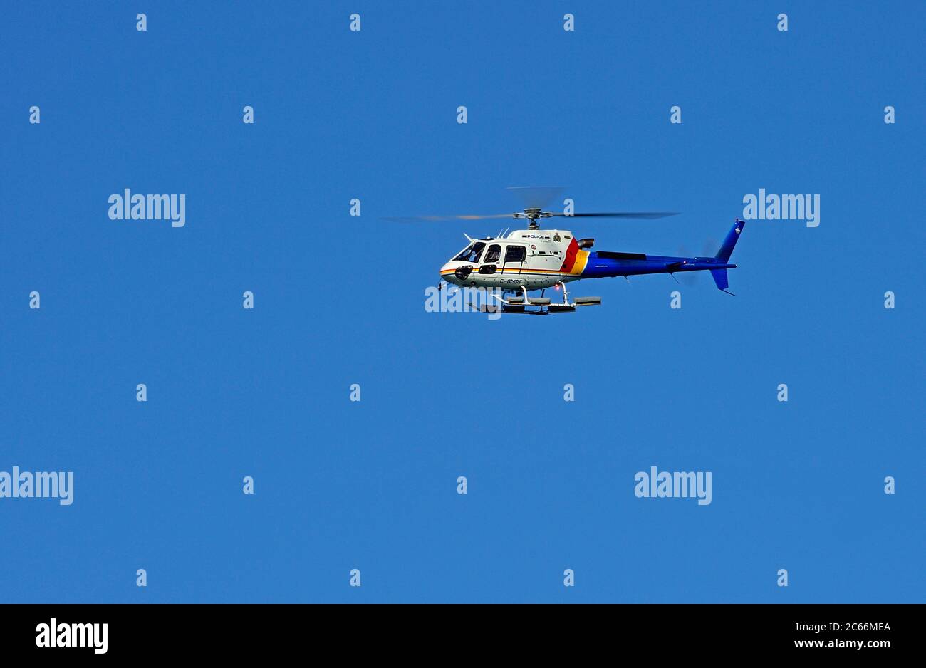 An RCMP police helicopter flying on a cloudless blue sky day Stock Photo