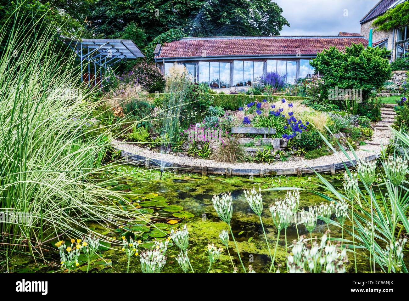An ornamental garden pond and terraced herbaceous borders in an English country garden. Stock Photo