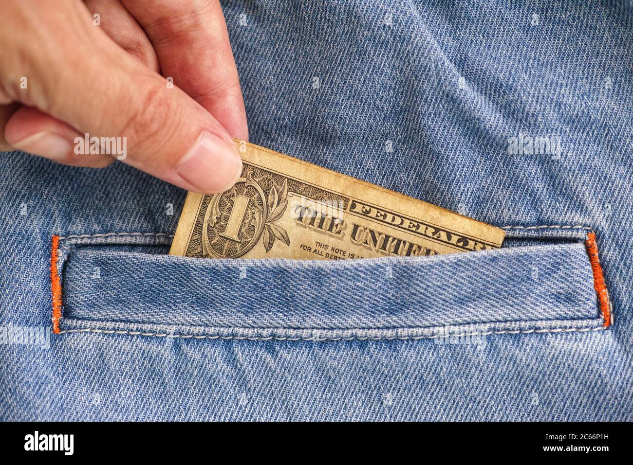 Person taking out a one dollar bill from jeans pocket. Close up. Stock Photo