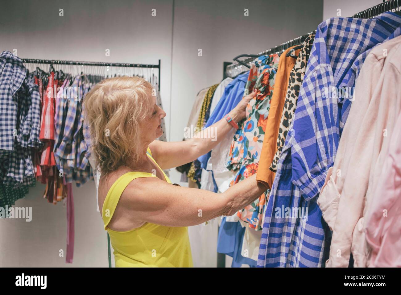 a mature woman choosing clothes in a fashion clothes shop Stock Photo