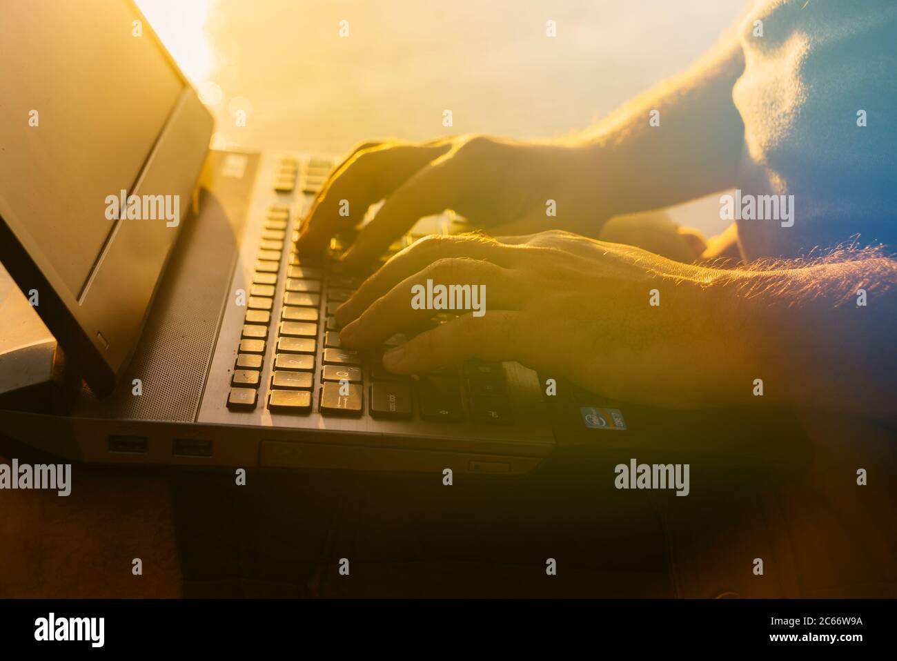 Man types on laptop sunset hi-res stock photography and images - Alamy