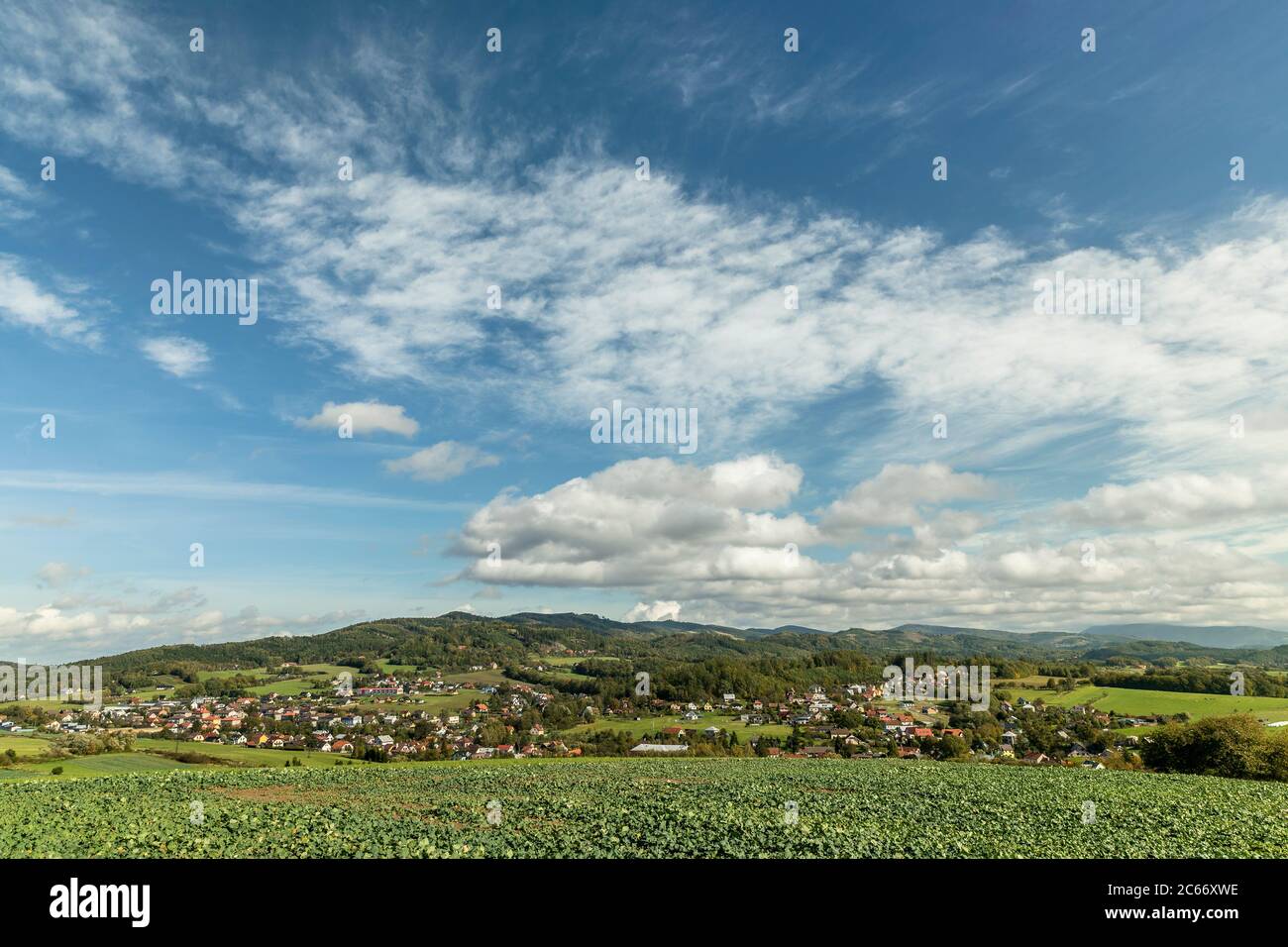Fast moving clouds in the sky captured during a sunny day overlooking the village and the high hills and mountains in the background foreground from a Stock Photo
