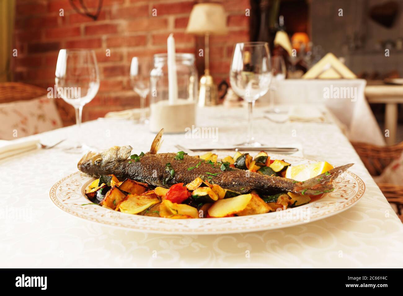 Grilled sea bass with vegetables on restaurant table, toned Stock Photo