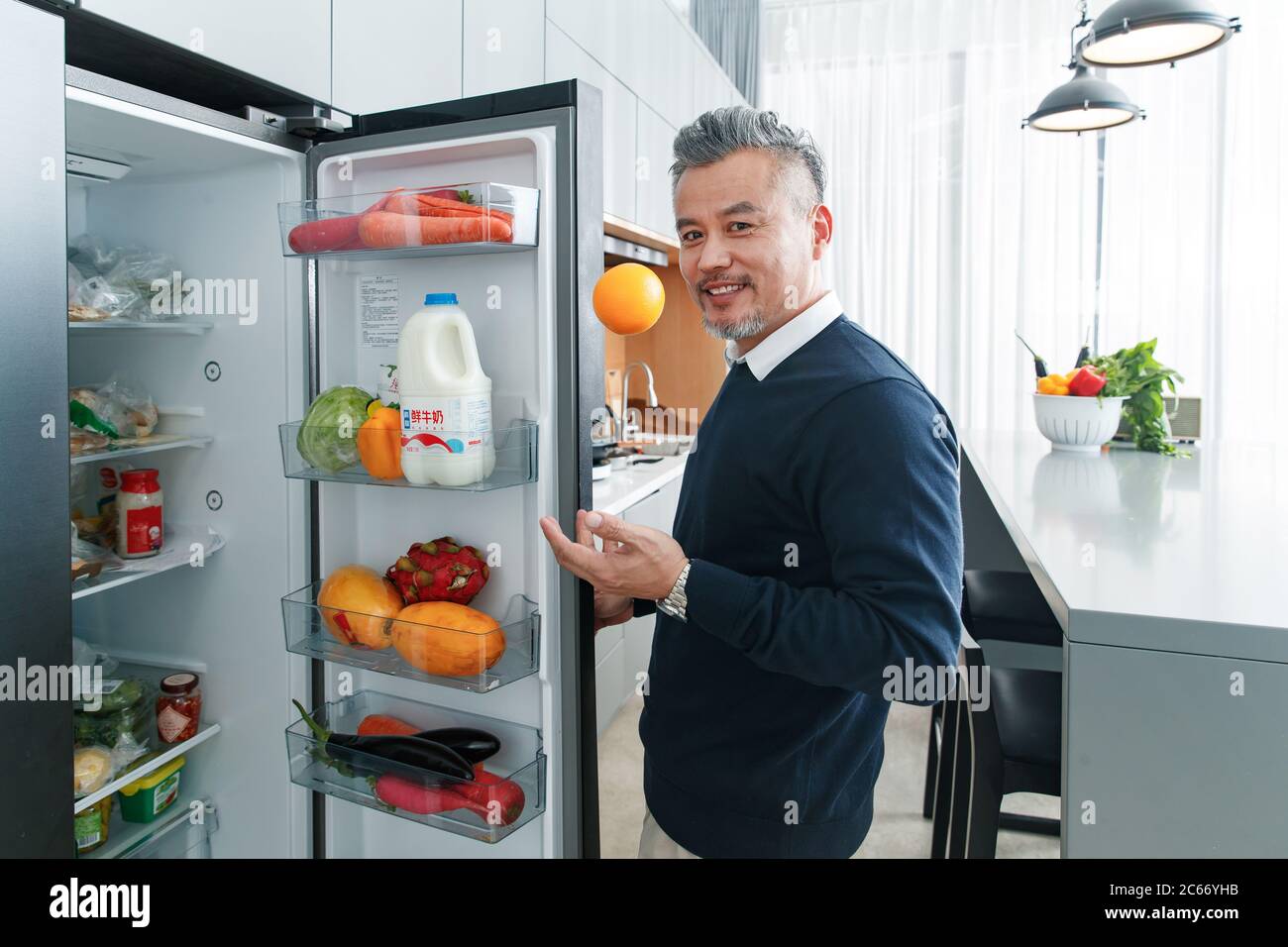 Middle-aged and old man open the fridge fruit Stock Photo